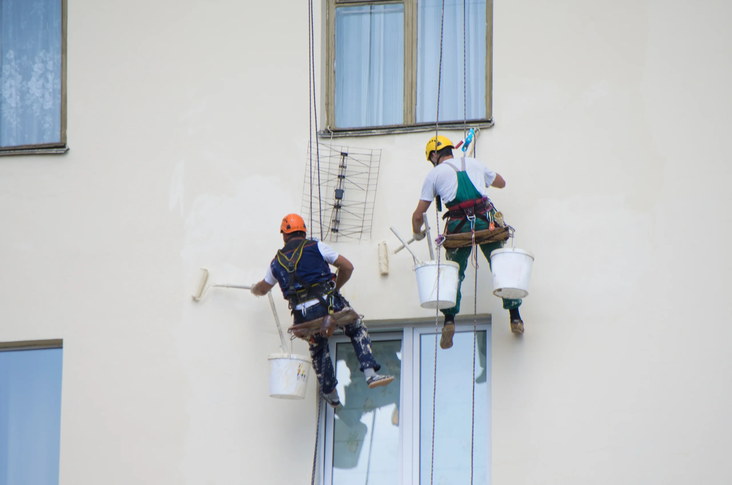 professional painters carrying out high-rise exterior wall painting using safety harness at adura paint emporium