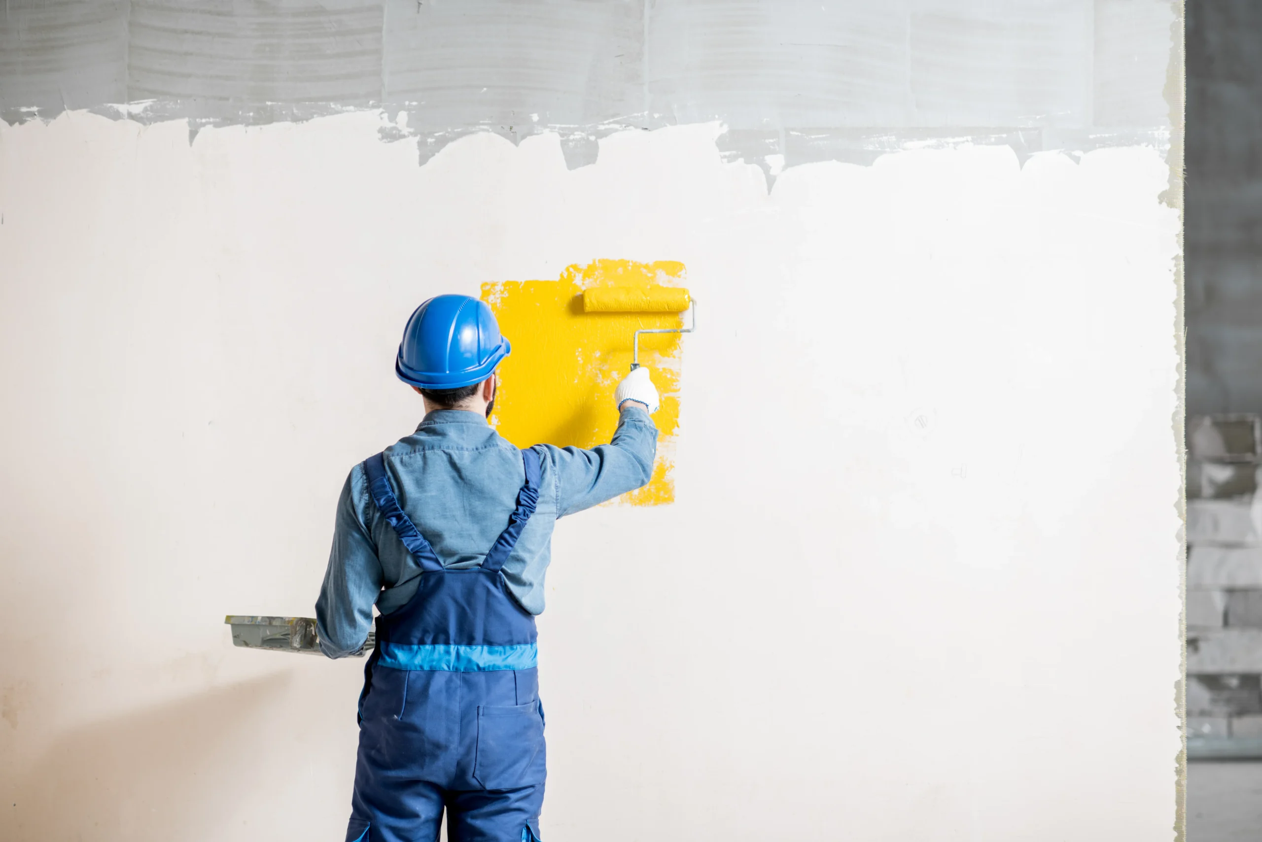 professional painter applying yellow interior wall paint with roller at adura paint emporium